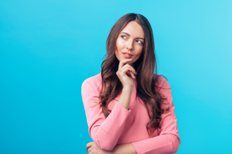 A beautiful woman looks to the side with her chin in her hand, as if considering a question.